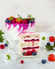 A festive pink cake. Berry cake for the party. Strawberries, blueberries, red currants. A pie on a white table. Cake for the holiday. A piece of cake on a saucer. Birthday