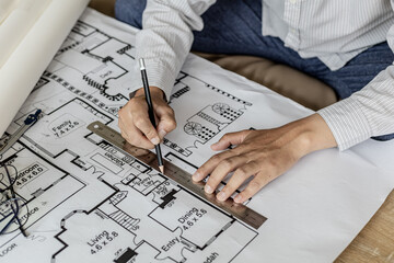 Architect uses a ruler to measure the blueprints of the houses he designed, designing the buildings...