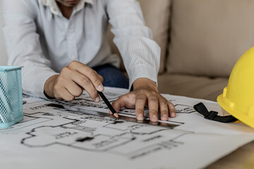 Architect uses a ruler to measure the blueprints of the houses he designed, designing the buildings...