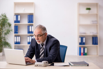 Naklejka premium Old male employee working in the office
