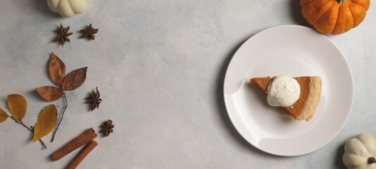 Top view of Thanksgiving dessert shows pumpkin pie with plate for holiday banner background.