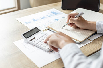 The financier uses a calculator and takes notes in a notebook, he is listing the errors in the...