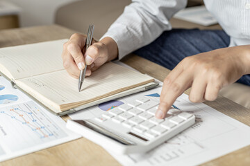 The financier uses a calculator and takes notes in a notebook, he is listing the errors in the financial documents to send to the finance department for review and correction. Financial audit concept.