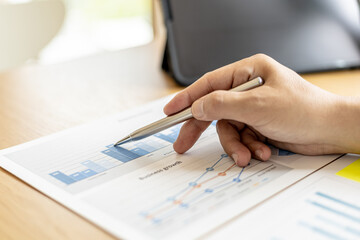 The financial officer uses a pen to point at the numbers on the financial documents to verify the correctness before submitting the information in the documents to the meeting. Finance concept.