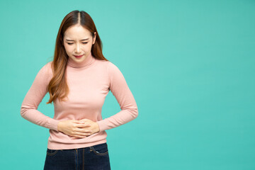 Asian woman holding on to her stomach isolated on green background, Pain and colic during...