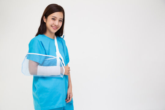 Young Asian woman wearing patient outfits and put on a soft splint due to a broken arm isolated on white background, Personal accident concept