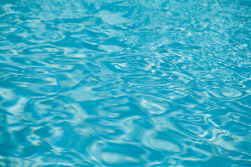 Hotel swimming pool with sunny reflections,sea wave close up, low angle view,blue water background.