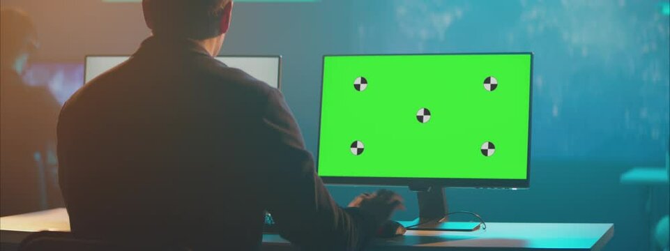 A mock-up green screen computer monitor at the dark atmosphere modern office.