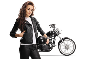 Fototapeta na wymiar Young female biker in a leather jacket holding a helmet and standing in front of a chopper