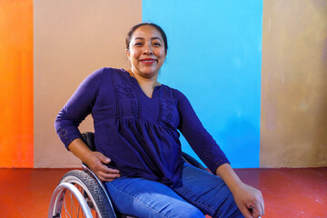 Middle-aged Hispanic woman with disabilities on a wheelchair against a colorful background