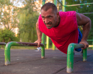 Fototapeta premium man training outside wearing red t-shirt and doing push ups