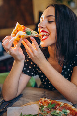 Young woman eating pizza in bar