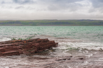 Dramatic scene with Sea waves, rocky seashore and clouds