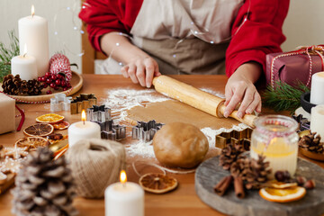 Young woman in process of baking christmas pastry, cutting cookies of gingerbread dough. Festive mood. Family culinary concept, cooking process, new year eve tradition. Holiday atmosphere of love.