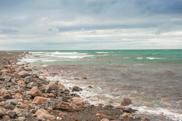 Dramatic scene with Sea waves, rocky seashore and clouds