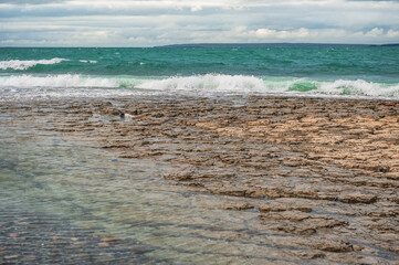 Dramatic scene with Sea waves, rocky seashore and clouds