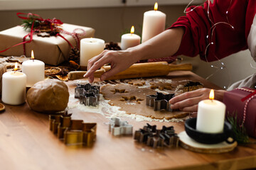 Young woman in process of baking christmas pastry, cutting cookies of gingerbread dough. Festive mood. Family culinary concept, cooking process, new year eve tradition. Holiday atmosphere of love.