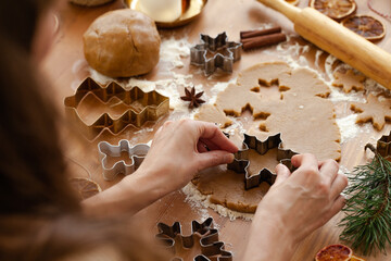 Young woman in process of baking christmas pastry, cutting cookies of gingerbread dough. Festive mood. Family culinary concept, cooking process, new year eve tradition. Holiday atmosphere of love.