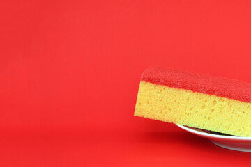 Yellow sponge on a plate, red background