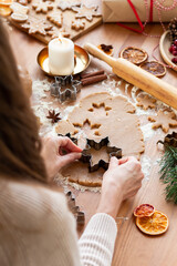 Young woman in process of baking christmas pastry, cutting cookies of gingerbread dough. Festive...
