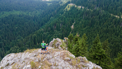 Back aerial view of Single father and son traveling together on cliff edge in Serbia. Son and Father lifestyle concept summer vacations outdoor aerial view Kopaonik, Serbia mountain top.