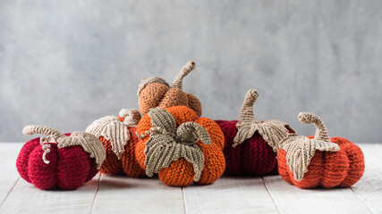 Handmade knitted pumpkins with leaves on white table