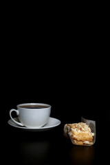 a cup of tea and French pastry isolatd on black background