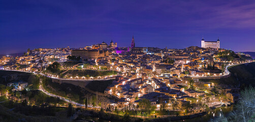 Fototapeta na wymiar Panoramic night view with violet and purple illumination for the international women's day of the ancient European city of Toledo, Spain.