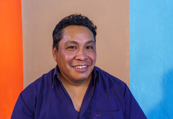 Portrait of a middle-aged Hispanic man smiling against a colorful wall
