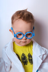 Little explorer. Boy plays scientist. Funny child with blue glasses. Cute, colorful photo. Kid portrait in doctor or science costume. Isolated picture.