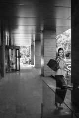 A beautiful girl with a handbag walks near the business center. Black and white
