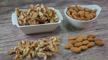 Nueces y Almendras en cuencos blancos sobre madera veteada