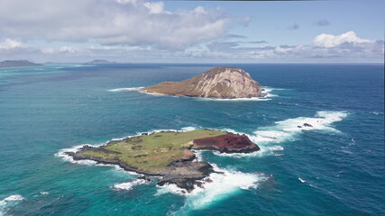 Flying drone over the ocean. View of Rabbit Island. Waves of Pacific Ocean wash over yellow sand of tropical beach. Magnificent mountains of Hawaiian island of Oahu.