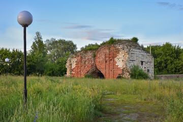 part of a ruined red brick wall surrounded by greenery