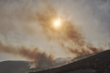 Summer forest fires. Smoke of a forest fire obscures the sun. Natural disasters. Bogsak, Mersin province, Turkey