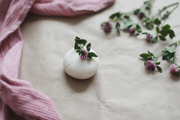 Natural organic soap with flowers and pink towel on craft paper background top view with copyspace
