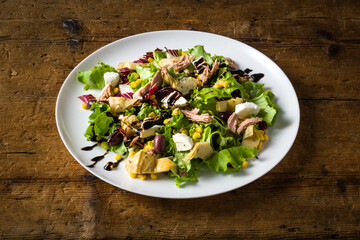 mixed salad platter with tuna, artichokes, corn, mozzarella, olives and icing.