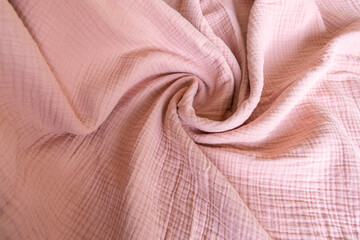 Soft muslin baby blanket background. Cotton clothing and textiles. Natural organic fabrics texture. Light pink rose color. Close up.