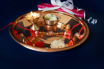 Indian festival: Raksha Bandhan background with an elegant Rakhi, Rice Grains and Kumkum Raksha bandhan with sweets gifts flowers and diya