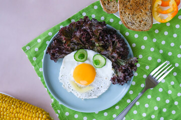 Fun Food for kids - smiling face of a clown made of scrambled eggs, cucumbers, corn and bell pepper for a healthy breakfast for children. Vertical photo of food
food for children
