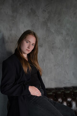 Fototapeta premium portrait of beautiful confident brunette woman in black in grey dark room. business woman. feminine. millennial people. stylish fashion clothes