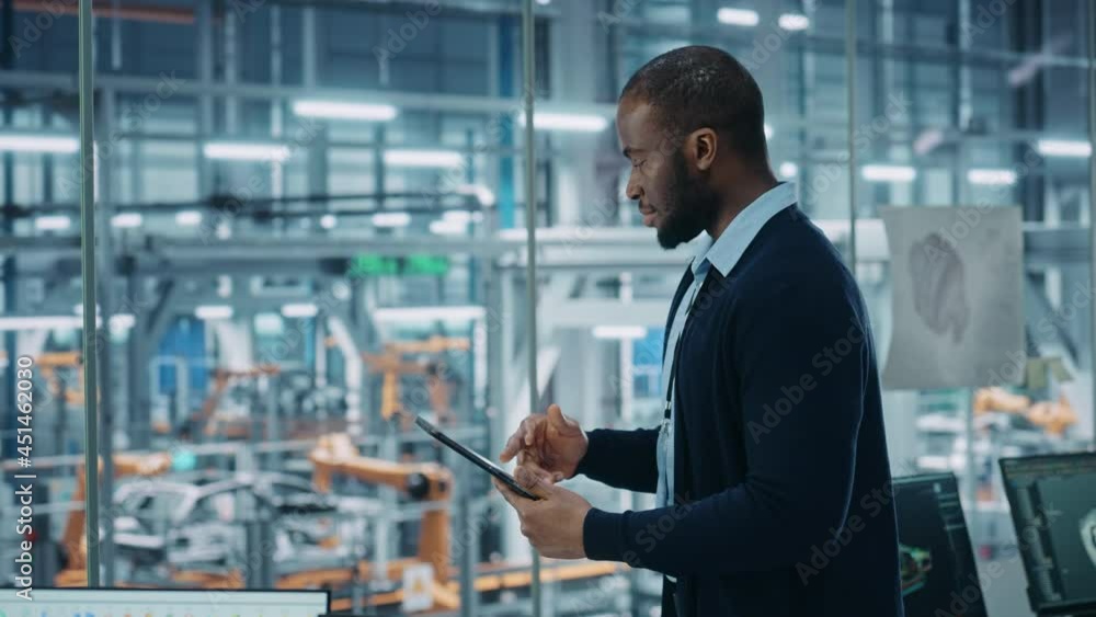 Poster car factory office: portrait of successful black male chief engineer using tablet computer in automa