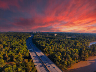 stunning aerial shot of miles of lush green trees, the freeway, the Chattahoochee river and blue sky at sunset with powerful clouds at the Chattahoochee River Recreation Area in Sandy Springs Georgia - obrazy, fototapety, plakaty