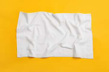 Crumpled white beach towel on yellow background, top view