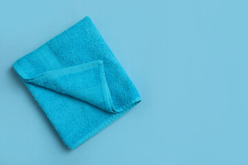 Folded soft beach towel on light blue background, top view. Space for text