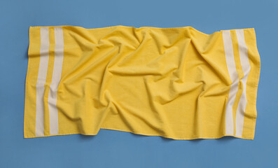 Fototapeta na wymiar Crumpled yellow beach towel on blue background, top view