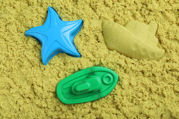 Fototapeta na wymiar Toys on yellow kinetic sand, flat lay