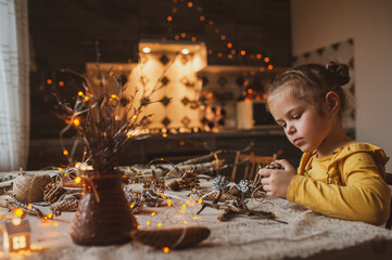 A cute sweet girl makes Christmas decorations from dried oranges, twigs and cones. Crafts for the holiday
