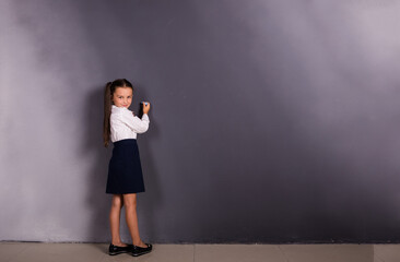 a small schoolgirl in a uniform stands at a blackboard with a place for text