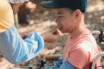 Smart handicapped teenager boy on wheelchair and friends on nature outdoors with sensory therapy in hiking, Lifestyle of disabled kids with school of special children.